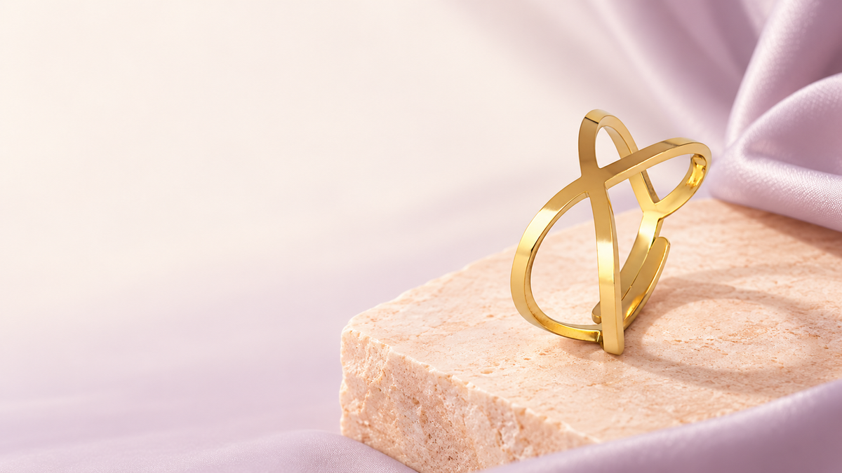 Bague croisée dorée sur une pierre pêche et un tissu lavande