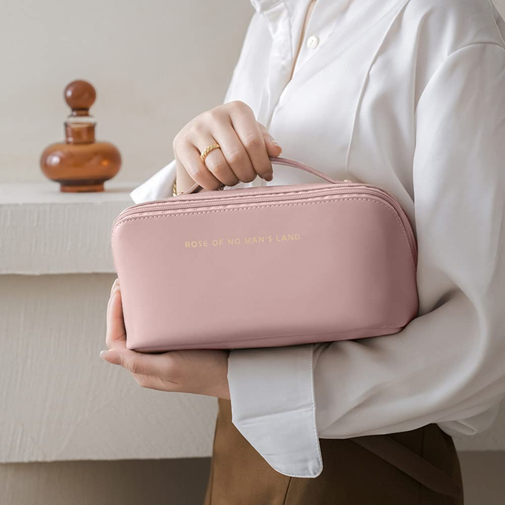 Trousse Nuage rose poudré tenue par sa poignée, avec son inscription dorée d’origine